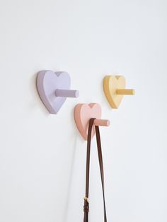 two heart shaped hooks hang on the wall next to a handbag and purse,