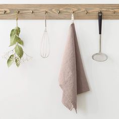 three kitchen utensils hanging on a wall next to a towel rack and spatula