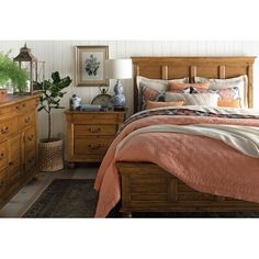 a bed room with a neatly made bed and wooden dressers next to a window