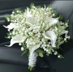 a bouquet of white flowers sitting in the back seat of a car with greenery