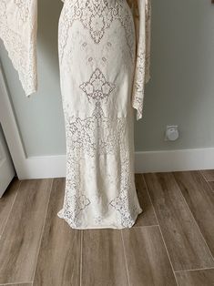 a woman's white dress on display in front of a door with an open jacket over it