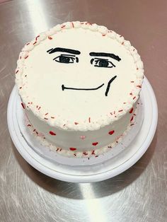 a white cake with red sprinkles and a face drawn on it