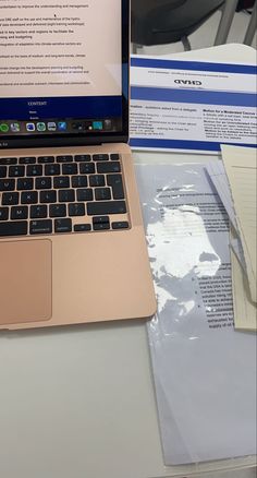 an open laptop computer sitting on top of a desk next to a pile of papers