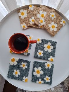 four crocheted coasters on a plate with a cup of coffee and napkins