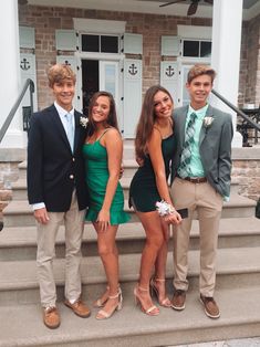 three young people standing on steps in front of a house, posing for the camera