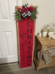 a red christmas sign hanging from the side of a door next to a wooden table