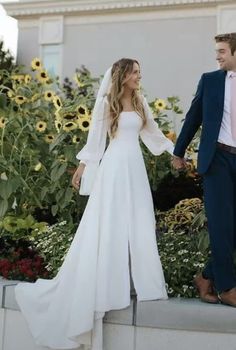 a bride and groom holding hands while standing next to each other in front of sunflowers