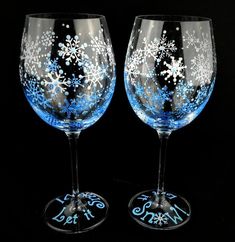 two wine glasses with snowflakes on them are sitting side by side in front of a black background