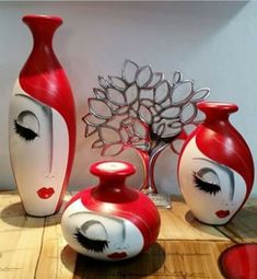 three red and white vases sitting on top of a wooden table next to each other