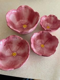 four pink flower shaped dishes sitting on top of a table