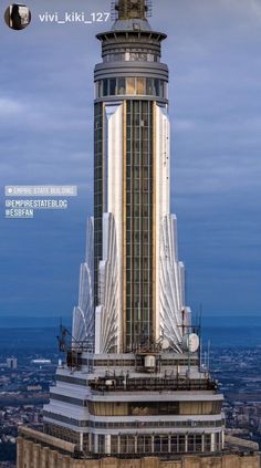 a tall building with a clock on the top of it's face in front of a cloudy sky