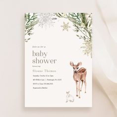 a baby shower card with a deer and snowflakes in the background, on a white surface