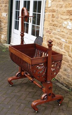 an old fashioned wooden cradle on wheels in front of a brick wall and white door