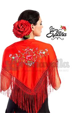 a woman wearing an orange and red shawl with flowers on the back, in front of