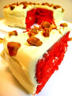 a slice of red velvet cake with white frosting and nuts