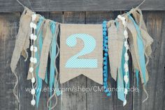 a number two banner with tassels hanging on a wooden wall in front of a fence