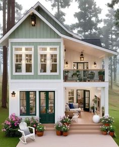 a house that is sitting in the grass with potted plants on the front porch