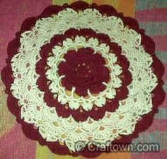 a crocheted doily is sitting on a pink and white tablecloths