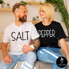 Custom made to order SALT or PEPPER unisex short sleeve couples t-shirt.  (Each shirt is purchased separately.) Photo shows Matte Black Design on Salt Shirt and Matte White Design on the Pepper Shirt. ADULT:  These soft and comfy shirts are high quality unisex shirts.  The unisex adult shirts are a slim semi-fitted cut.  So they are more slim and fitted for a man.  If you want a looser fit I suggest a size up.  They would run pretty true to a loose fit in womens sizing.  I have included the sizing charts by the manufacturers above in the photos.  Please take your favorite comfy shirt, lay it on a flat surface and compare the measurements of your favorite fitting shirt to the manufacturer's specs. KIDS:  These soft and comfy bodysuits and tees run pretty true to size to a little on the smal Black Cotton Couples T-shirt, Black Cotton T-shirt For Couples, Couples Cotton T-shirt Gift, Couples Cotton T-shirt For Gift, Funny Short Sleeve Tops With Custom Text, Family Matching Short Sleeve T-shirt With Custom Text, White Short Sleeve Couples T-shirt, White Matching Couples T-shirt, Couples White Short Sleeve T-shirt