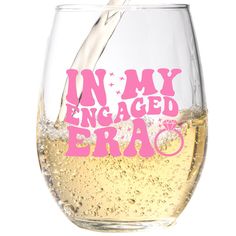 a wine glass filled with white wine being poured into it that says in my engaged bra