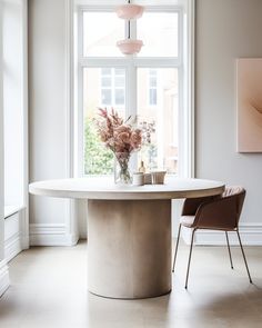 a white table and chairs in front of a large window with pink flowers on it