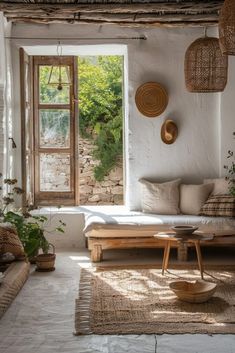 a living room filled with lots of furniture and plants on top of a rug next to an open window