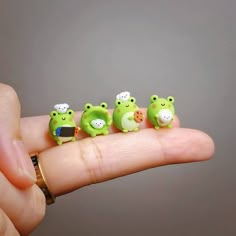 five little green animals sitting on top of each other in someone's hand,