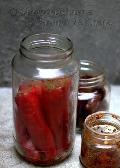 jars filled with red peppers sitting on top of a table