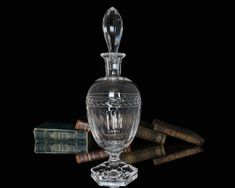 an empty glass bottle sitting next to some books and corks on a black background