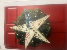 a red door with a wreath and two star shaped signs hanging from it's side