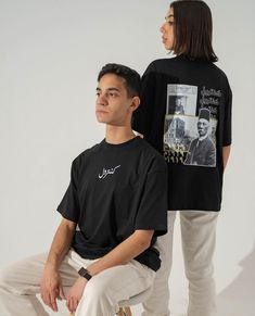 a man sitting next to a woman wearing a black t - shirt and white pants