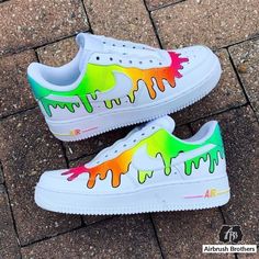 a pair of white sneakers with rainbow paint drips on the upper part of them