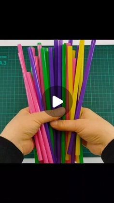 someone is holding up several colored straws in their hands, with the video below