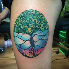 a colorful tree tattoo on the thigh