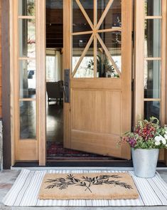 a potted plant sits on the front door mat in front of an open wooden door