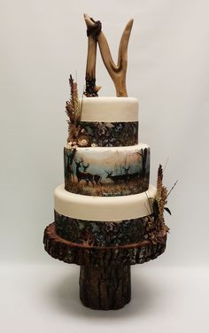 a three tiered cake decorated with deer and trees