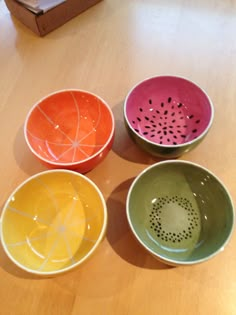 four colorful bowls sitting on top of a wooden table