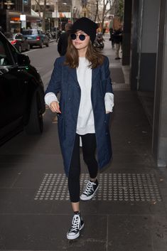 a woman walking down the street wearing black and white sneakers