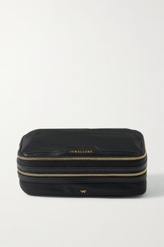 a black cosmetic bag with gold zippers on the front and bottom, sitting against a white background