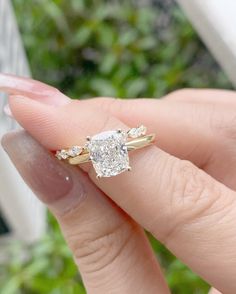 a woman's hand holding an engagement ring in front of her face, with the diamond