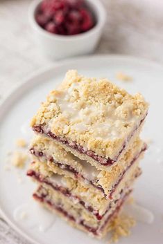 three dessert bars stacked on top of each other with raspberries in the background