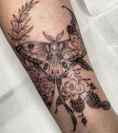 a butterfly with flowers and leaves on the arm is shown in black and grey ink