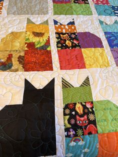 a black cat is sitting on top of a quilt