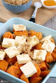 a blue bowl filled with butter and cubed tofu on top of a wooden table