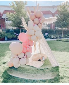 a teepee tent made out of balloons in the grass