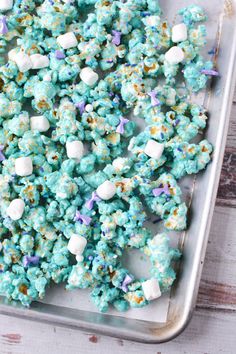 blue popcorn with marshmallows and sprinkles on a baking sheet