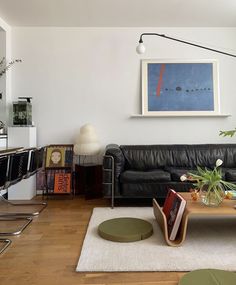 a living room filled with furniture and a painting on the wall above it's coffee table