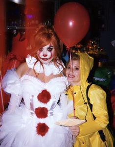 two women dressed in costumes posing for the camera with one holding a plate and balloon