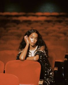 a woman sitting in an auditorium with her hand on her head