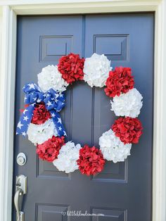 a patriotic wreath with red, white and blue flowers on the front door for memorial day